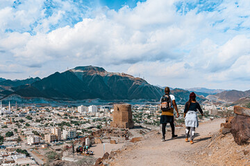two hikers walking through al-rabi hiking trail and viewing the khor fakkan mountains in sharjah, ua