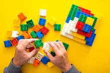 Hand Stacking Up The Colorful Plastic Block On Yellow Background