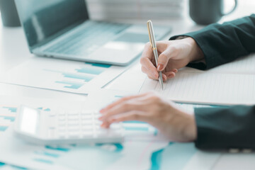 Businesswoman or accountant using the phone to check business information. Accounting Documents and Laptop Computer at Office Business Ideas