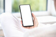 © Celt Studio - woman user customer hold cellphone mockup with white screen in hand. cell mobile phone blank white screen mockup. in white clothes