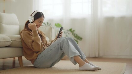 Poster - Happy young asian woman relaxing at home. Female smile sitting on sofa and holding mobile smartphone. Girl using video call to friend