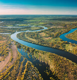 Fototapeta Na ścianę - Village Near River, Aerial View Green Forest Woods And River Landscape In Sunny Spring Summer Day. Top View Of Nature, Bird's Eye View. Trees Standing In Water During Spring Flood floodwaters. woods