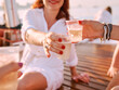 young women hands holding plastic glasses with sparkling wine during travelling on yacht. plastic, environment, recycling, toast, party concept