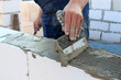 The bricklayer applies the adhesive before stealing the bricks or building blocks. The concept of building a house.