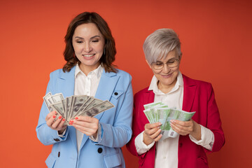 Wall Mural - two joyful adult women with euros and dollars in their hands	