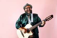 Happy Bearded Man Playing Acoustic Guitar On Pink Background.