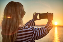Woman Traveler Tourist Using Smartphone, Taking Photo Of Sea View At Sunset In Summer Day. Enjoying European, Famous Popular Touristic Place In World.
