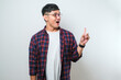 © Reza - Young handsome asian man pointing with hand finger to the side looking at the camera.