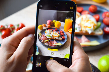 Taking a photo of a poached benedict egg on an avocado toast for a social media post.