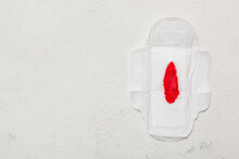 Women Hygiene Products Or Sanitary Pad With Red Feather On Colored Background. Pastel Color. Closeup. Empty Place For Text. Female Daily Hygiene