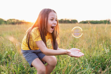 Happy smiling little girl playing in the green meadow on a sunny summer day, child happiness