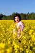 © AliaksaB - Beautiful young woman in the middle of a field of yellow rapeseed or canola flowers.