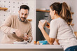 © dusanpetkovic1 - A man adding salt in breakfast while standing in kitchen with girlfriend.
