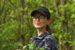 © Kseniia - Portrait of traveler smiling young woman in black cap and glasses breathing fresh air in the green spring forest.