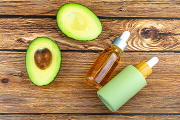 Avocado and two cosmetic bottles with oil on a wooden table. Concept of natural cosmetics and skin care.