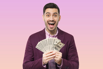 Wall Mural - Successful excited man in suit holding bunch of money cash isolated over pink background