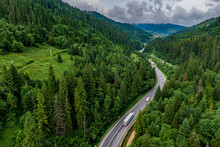 Cargo Truck On The Higthway. Cargo Delivery Driving On Asphalt Road Through The Mountains. Seen From The Air. Aerial View Landscape. Drone Photography.