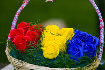 A traditional Romanian basket with roses in the color of national flag of Romania, blue yellow and red. Symbol for the Romanian National day.