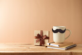 Fototapeta Kawa jest smaczna - Father's day concept with coffee cup, mustache, notebook and gift box over beige background