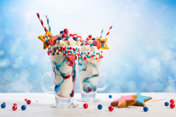 Wall Mural - Crazy milk shake with ice cream,whipped cream, marshmallow,cookies and colored candy in glass. Sweet dessert for Fourth of July. Idea milkshake for Patriotic day.