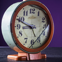Dirty Old Broken Rusty Alarm Clock. Broken Dial. Red Body Violet Background. Square