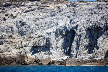 Wall Mural - Aegean Sea. Rocky coast, cliff and cave, ripple ocean. Cyclades Greece. Seascape near Mykonos island