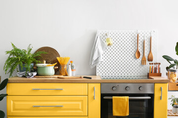 interior of modern kitchen with yellow furniture, oven and peg board