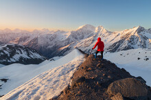 Snow-covered Peaks At Sunrise With Lonely Man On Dark Edge Of Mountain, Caucasus, Russia