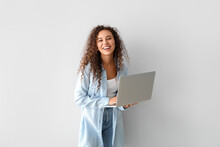 Happy Young African-American Woman Using Laptop On Light Background