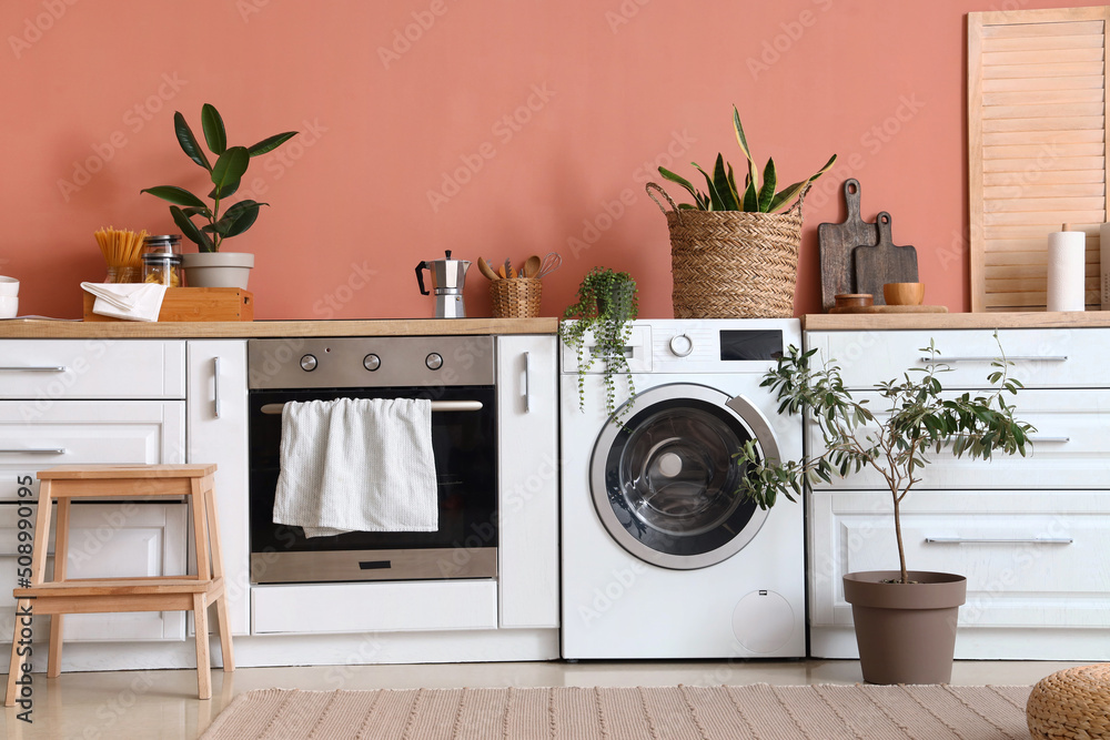 Stylish interior of kitchen with modern washing machine