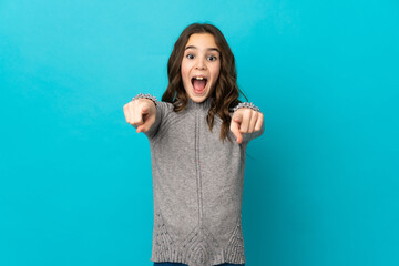 Wall Mural - Little caucasian girl isolated on blue background surprised and pointing front