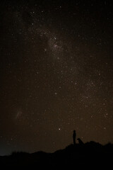 silhouette of a man standing in the starry night with his dog