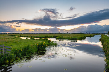 Wall Mural - beautiful clouds and calm water in the dutch polder landscape at sunset
