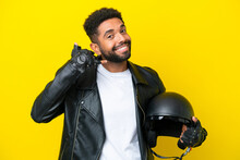 Young Brazilian Man With A Motorcycle Helmet Isolated On Yellow Background Making Phone Gesture. Call Me Back Sign