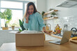 © gstockstudio - Surprised young woman unpacking box while standing at the domestic kitchen