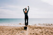 © Cavan Images - man zipping up his wetsuit at the beach ready to swim in the sea
