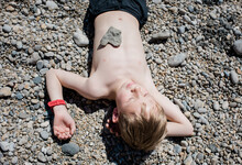 Boy Laying On Stones Witha Heart Shaped Stone On His Heart