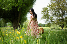 Beautiful Asian Woman Carrying A Picnic Basket In A Field In Summer