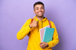 Young student Brazilian man isolated on purple background giving a thumbs up gesture