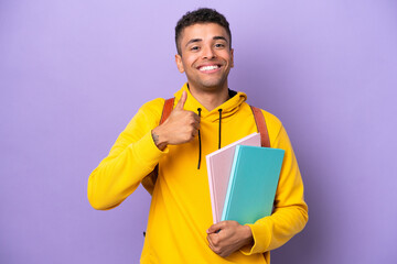 Wall Mural - Young student Brazilian man isolated on purple background giving a thumbs up gesture