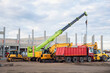 © Kirill Gorlov - Many different multiclored colorful heavy industrial machinery equipment at construction site parking area against warehouse building city infrastructure development. Commercial vehicles rental sale