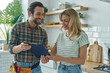 © gstockstudio - Beautiful young woman signing document while communicating with handyman at the kitchen