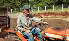 Latin Farmer With A Hat Driving Tractor On The Farm.