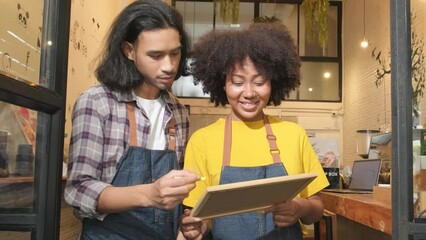 Wall Mural - Two young startup barista partners with aprons stand at casual cafe door, write on board and show an open sign, happy and cheerful smiles with coffee shop service jobs, and new business entrepreneurs.