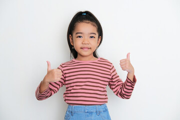 Wall Mural - Asian little girl smiling to the camera and give two thumbs up