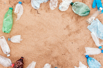 Wall Mural - Ecology template. Frame from plastic dirty bottles. Sandy background with copy space. Flat lay. The concept of environmental protection and Earth Day