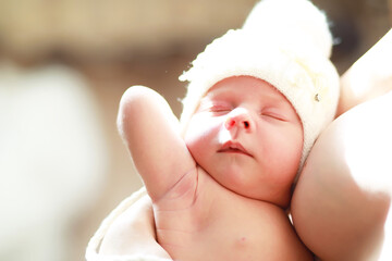 Wall Mural - A newborn baby lies in her mother's arms. A beautiful baby of European appearance is sleeping.