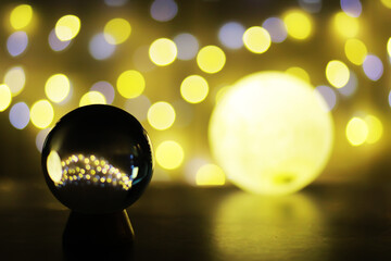 Crystal Ball on the table with bokeh, lights behind. Glass ball with colorful bokeh light, prediction concept.