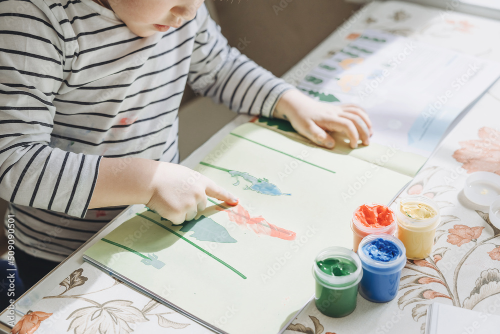 Finger painting. Cute little boy painting with fingers at home. Close