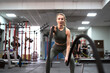 Young woman  exercising with battle ropes on a gym